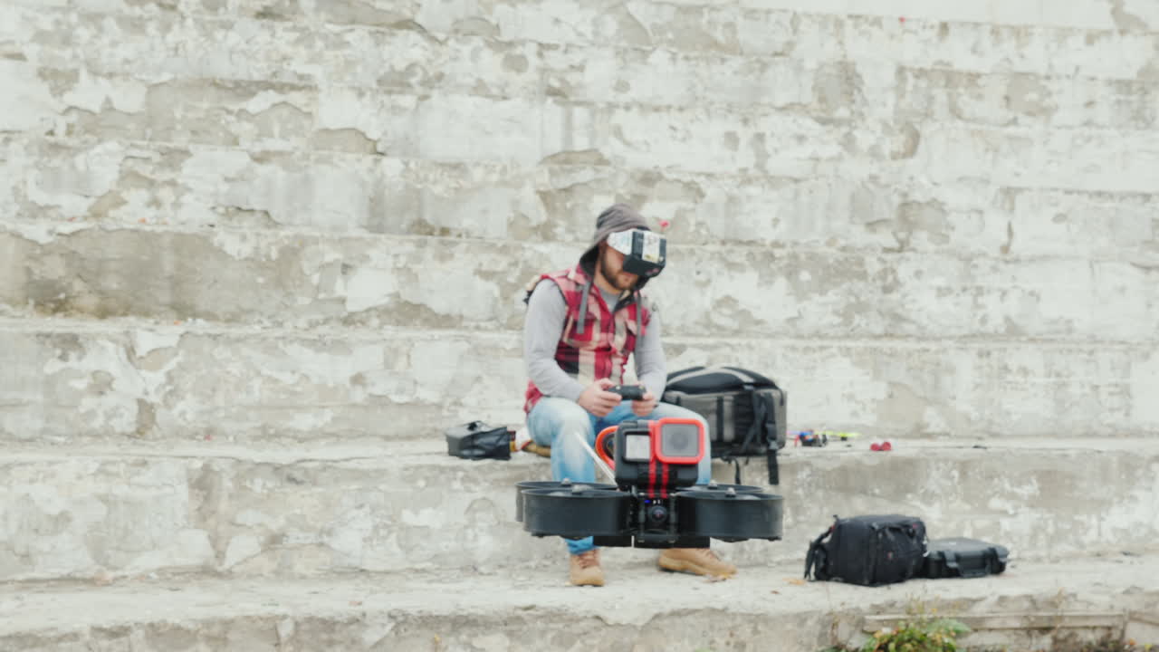 un hombre pilotea un dron en un casco con una pantalla de video pilotaje deportivo en primera persona