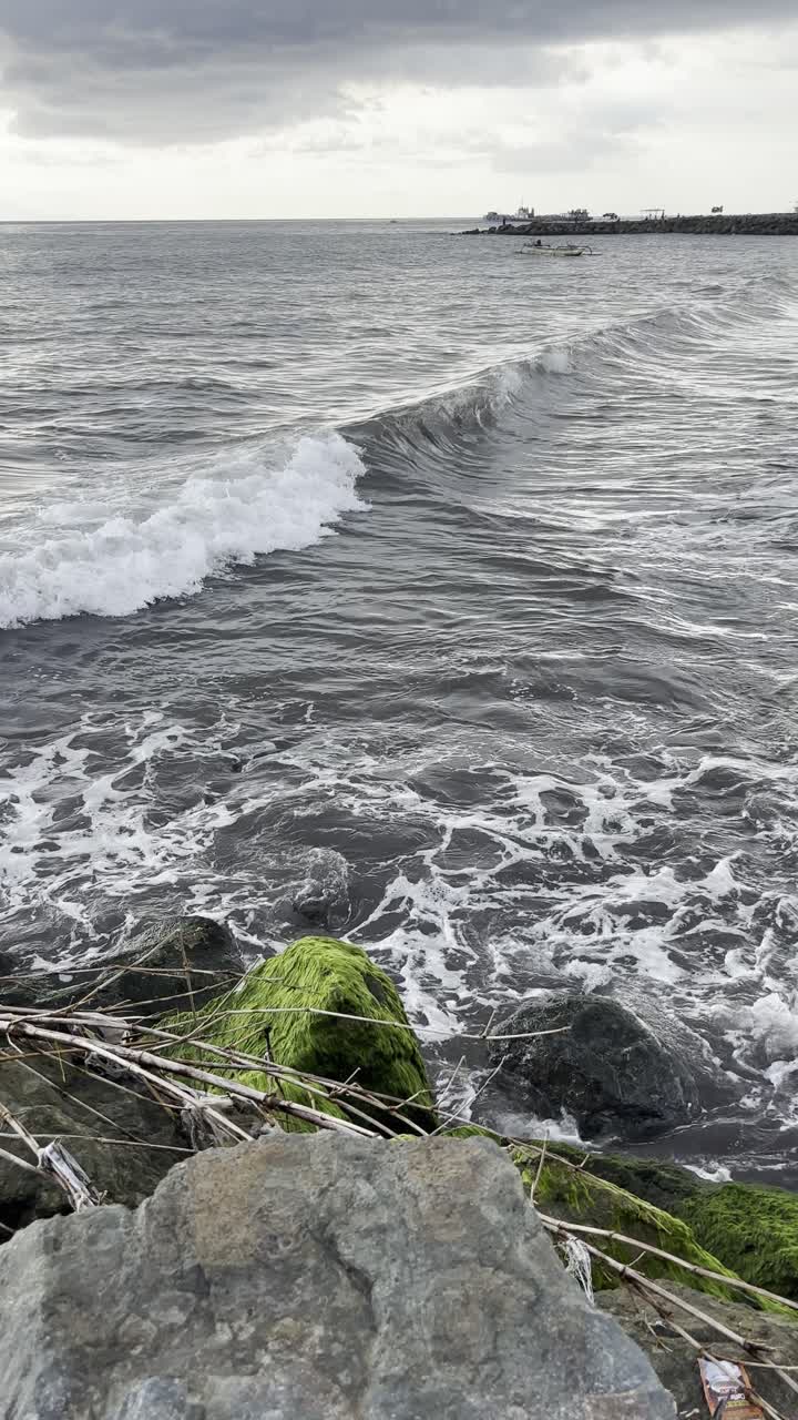 Onde dell'oceano che si infrangono su scogli muschiosi lungo un litorale nuvoloso