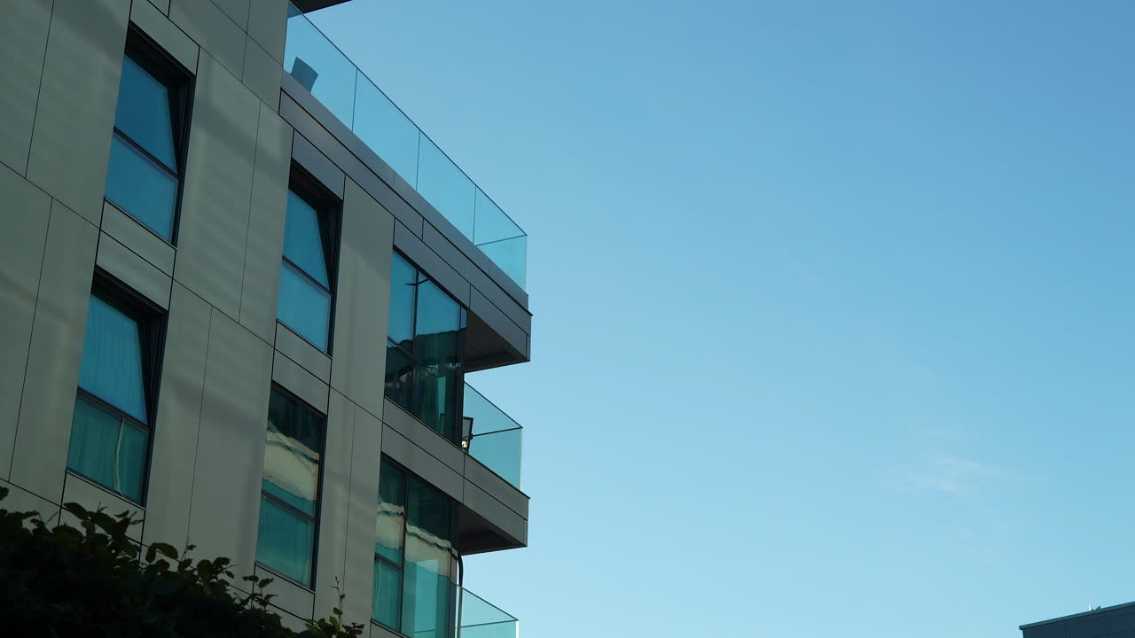 Modern balconies with transparent glass barriers jutting out from a building's stone facade