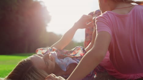 cheerful woman spending time with cute girl in city park