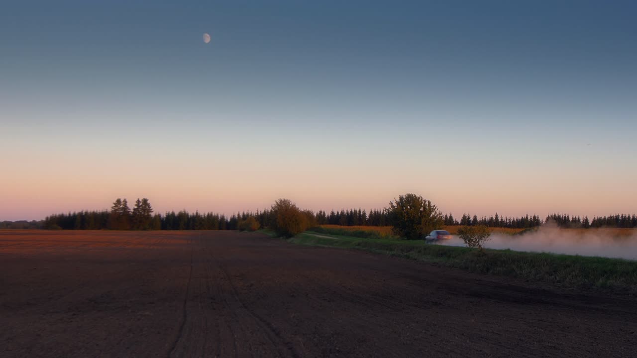 Kveldsbilde av en raskt kjørende bil på en støvete vei
