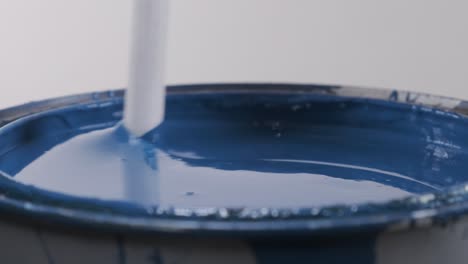 close up of plastic stick stirring blue paint