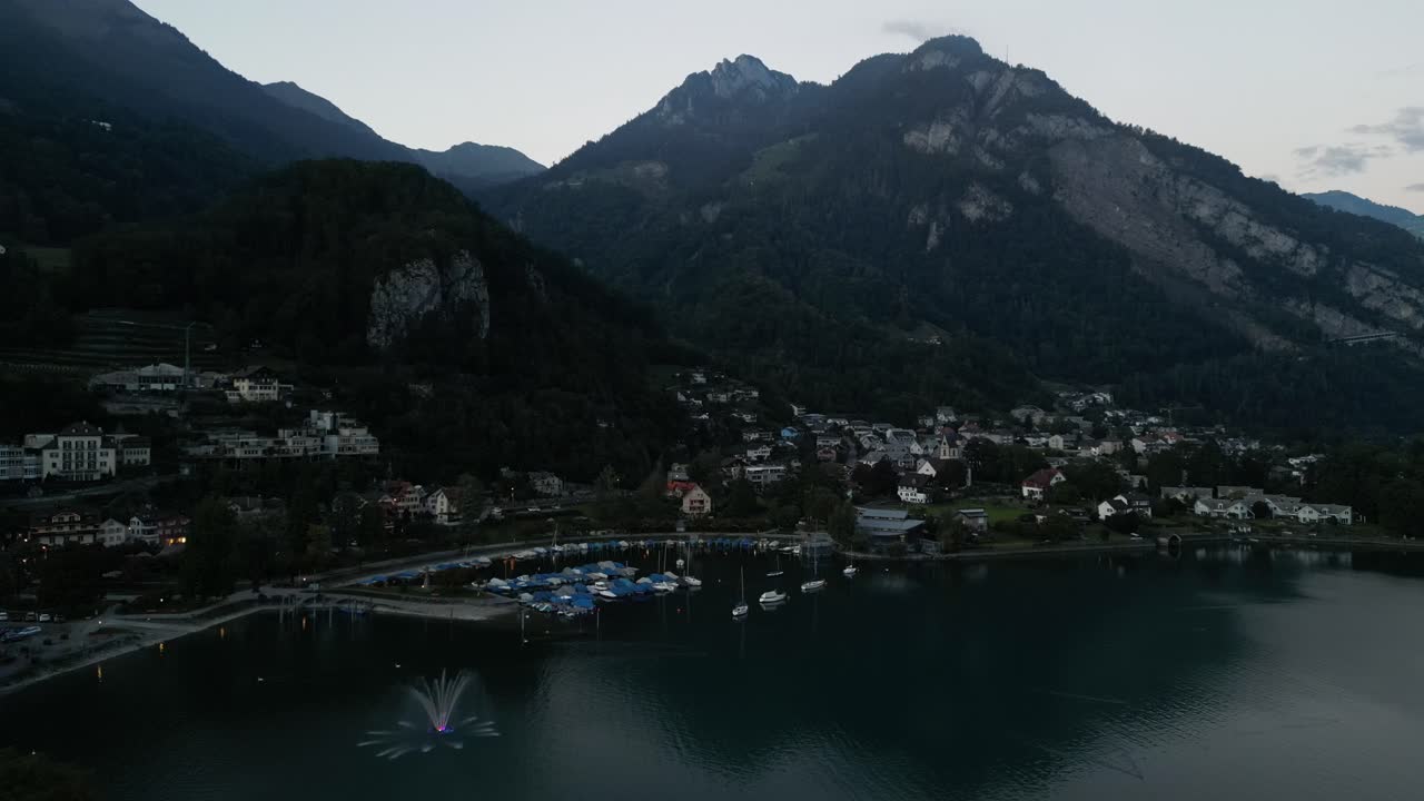 clip aéreo del lago en el valle alrededor de los picos de las altas montañas con una fuente y muchos deportes acuáticos