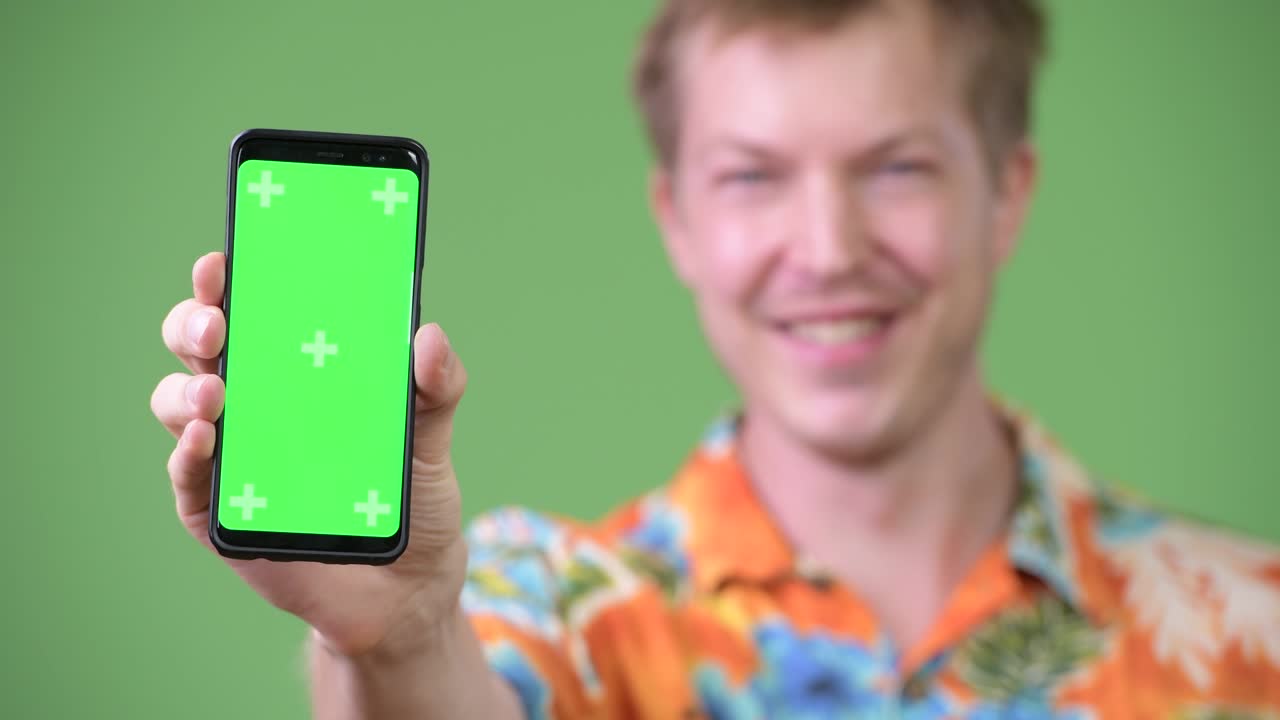 Young happy handsome tourist man smiling while showing phone