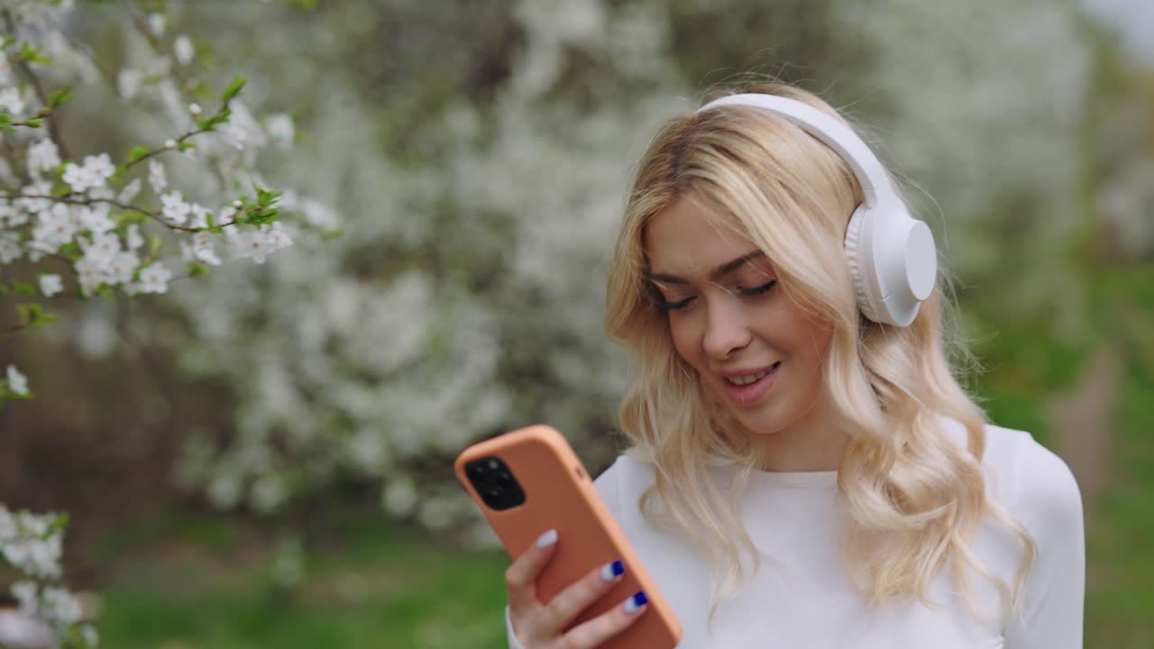 Woman Listening to Music on Phone in a Spring Park
