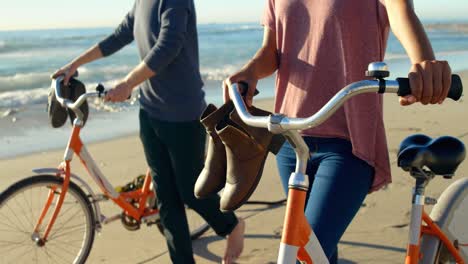 pareja con bicicleta caminando en la playa 4k