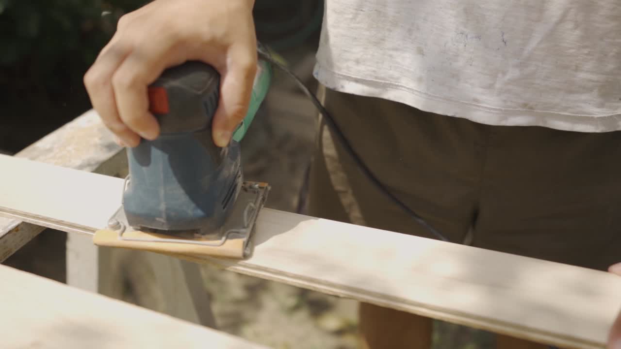 man Using Electric Sander for wood in a carpentry outdoors, wood work, slow motion