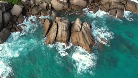 Moving-bird-eye-drone-shot-of-hidden-beach-near-north-east-point-beach,-huge-rock-boulders,-white-sandy-beach-and-turquoise-water,-Mahe-seychelles-60fps