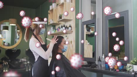 animation of coronavirus cells over caucasian female hairdresser and woman wearing face masks