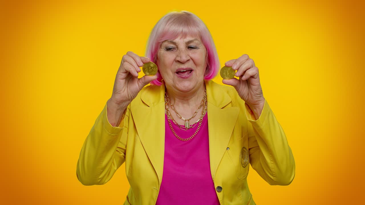 Anziana signora nonna elegante che mostra bitcoin d'oro, investimento in criptovaluta, tecnologia di mining.