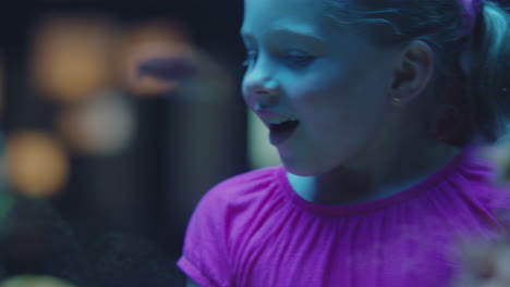 happy girl in aquarium looking at tropical fish curious child watching colorful sea life swimming in tank learning about marine animals in underwater ecosystem cute kid at oceanarium