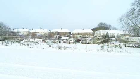 Parcelas-Cubiertas-De-Nieve-Con-Casas-Detrás