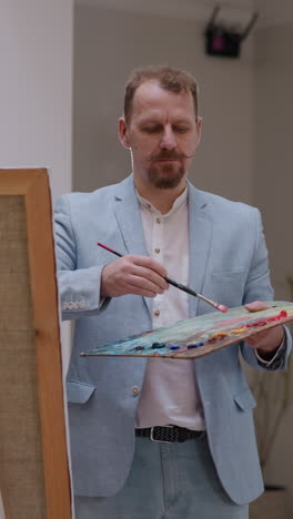 el productor de arte dibuja el retrato de la modelo en el estudio. el maestro talentoso con la losa de pigmento de color trabaja en la pintura por caballete en la sala de luz. sesión de modelo de vida