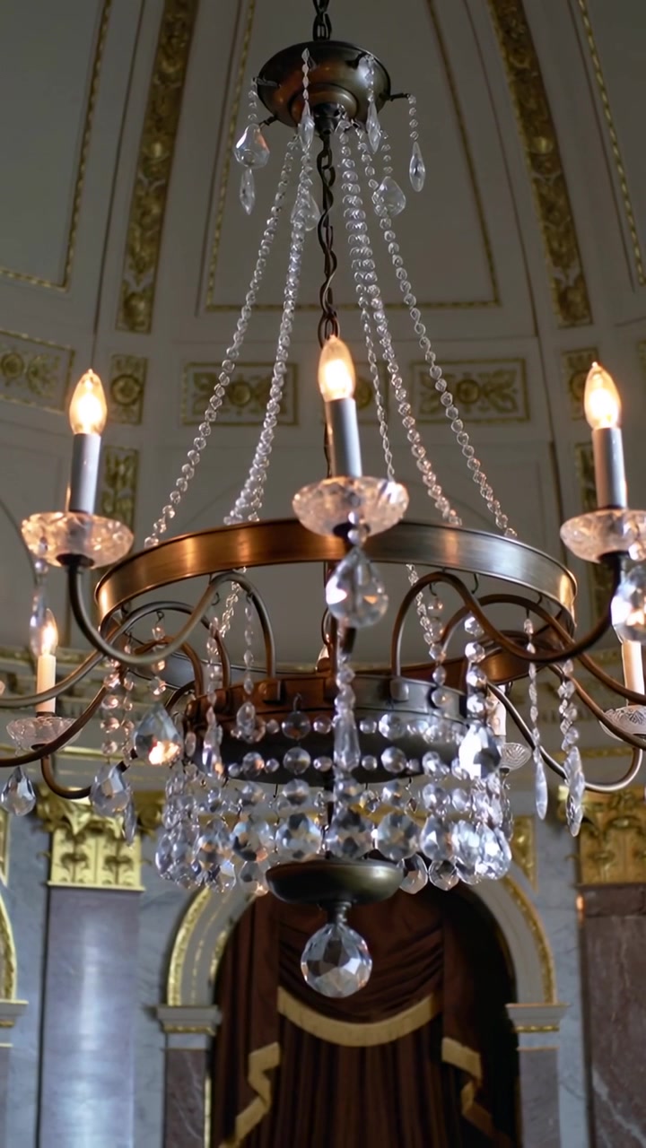Video verticale: Telecamera panoramica che mette a fuoco un lampadario di cristallo in una sala storica, rivelandone i dettagli.