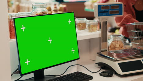 Merchant-selling-goods-next-to-pc-with-greenscreen-at-checkout