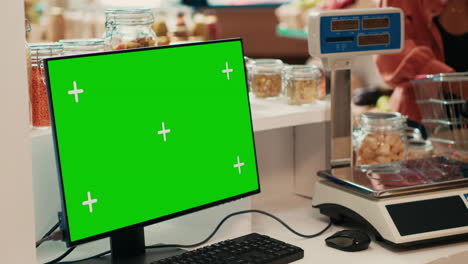comerciante que vende bienes al lado de la pc con pantalla verde en la caja