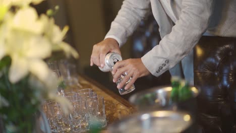hombre vertiendo bebida de una lata en un vaso en la mesa servida en una fiesta de bodas