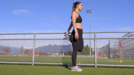 mujer joven en forma estirando los isquiotibiales doblando el pie antes de hacer ejercicio