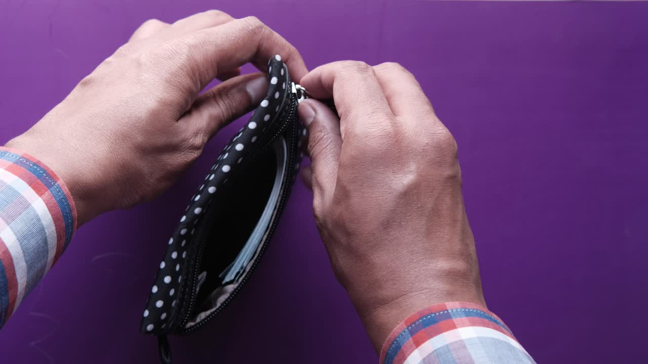 Person opening a polka-dot purse containing money.