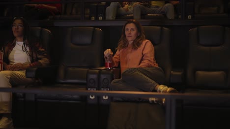Woman-sitting-in-armchair-watching-a-movie-at-the-cinema-alone