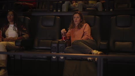 woman sitting in armchair watching a movie at the cinema alone