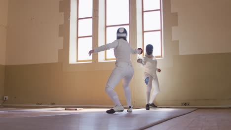 atletas de esgrima durante un entrenamiento de esgrima en un gimnasio