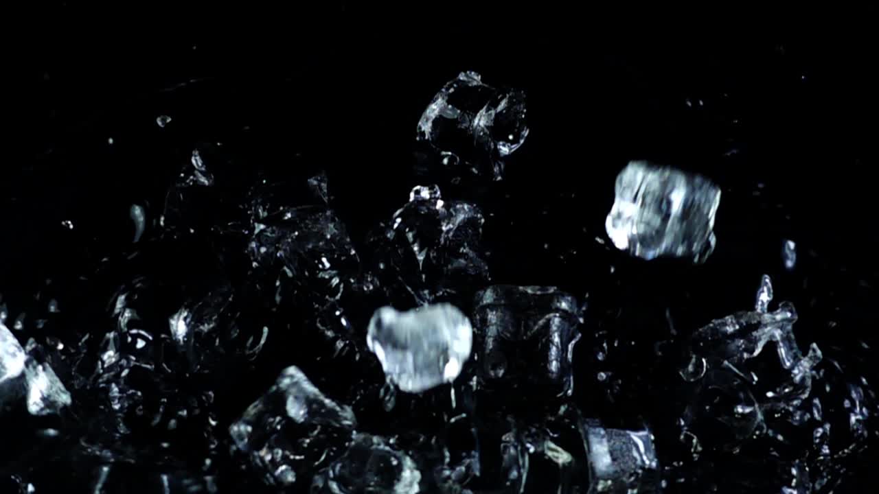 Vallende ijsblokjes op een zwarte achtergrond. Slowmotion