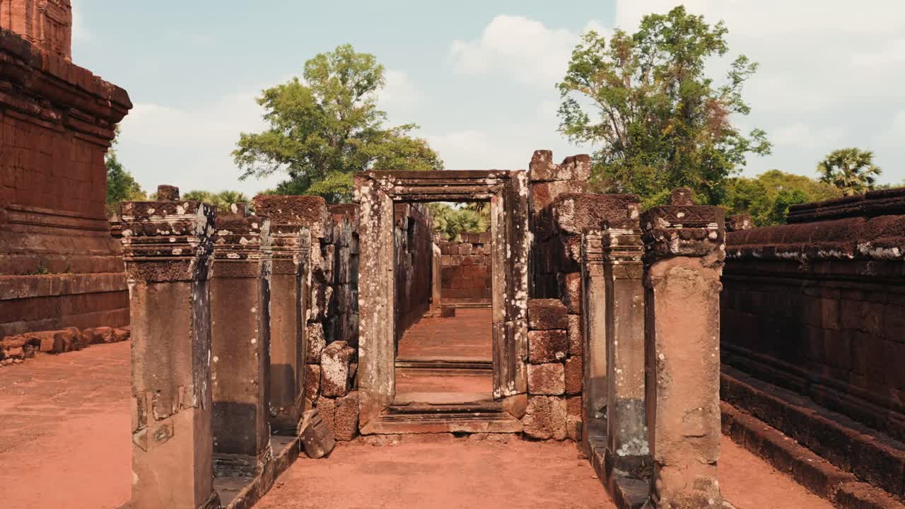 Une vue cinématographique des ruines de l'ancien temple d'Angkor Wat au Cambodge, mettant en lumière les structures en pierre altérées par le temps, les sculptures détaillées et la nature envahissante. La vidéo met en valeur la grandeur historique