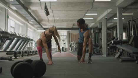 vista frontal de una mujer caucásica y un atlético afroamericano en el gimnasio.