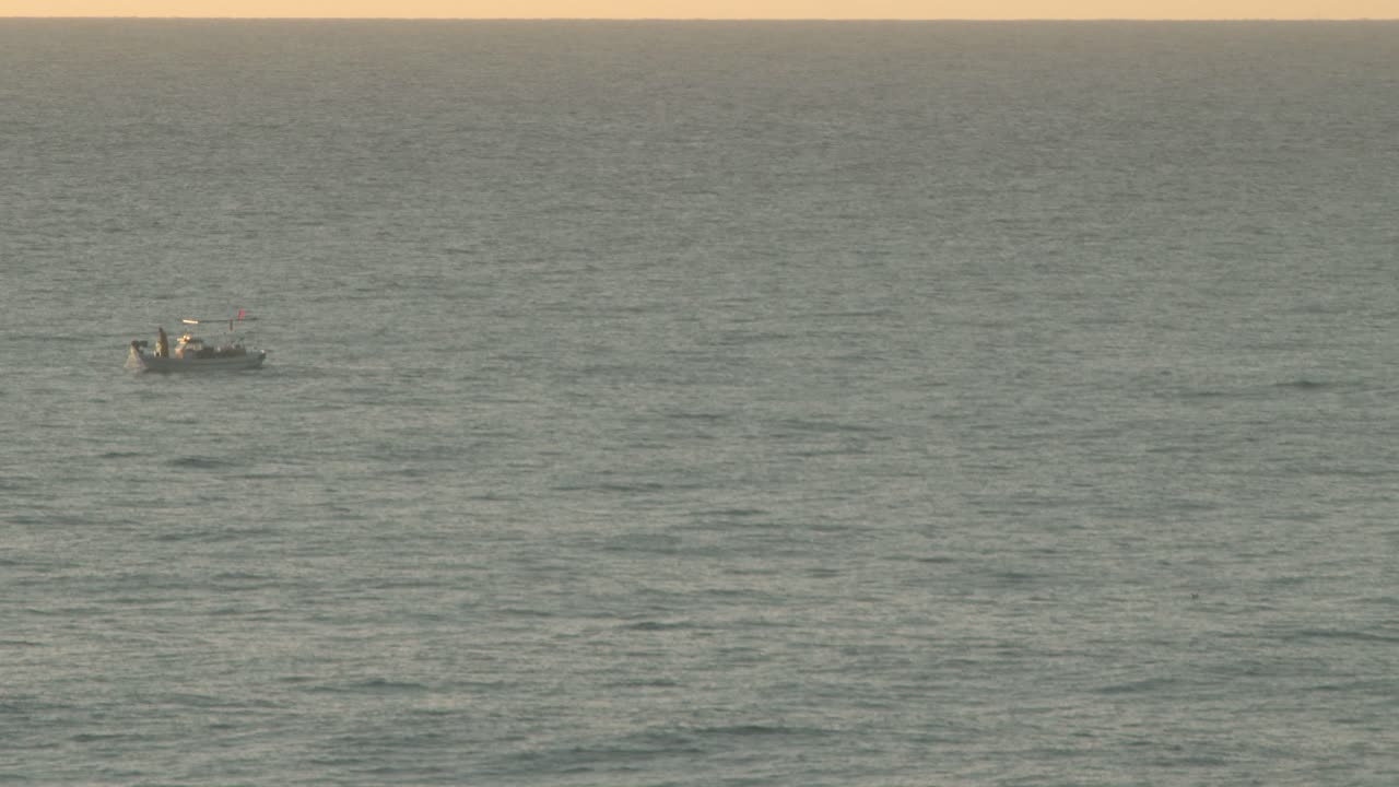 A lone fisherman works from his fishing trawler at sunrise