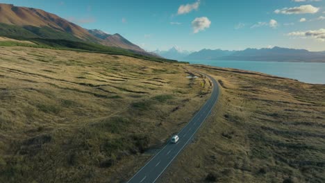 aerial view of white campervan traveling along remote scenic road with a view of aoraki mount cook in south island of new zealand aotearoa