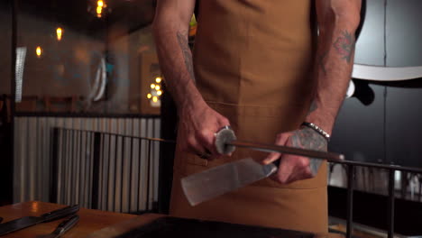 male tattooed latin model sharpen barbecue butcher knife slider shot slot motion