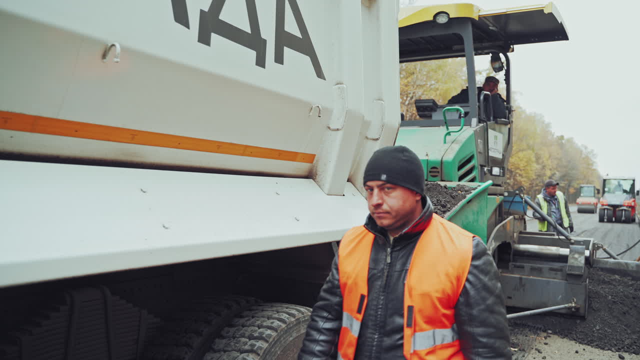 Building of new asphalt road. Road construction works with steamroller machine and asphalt finisher