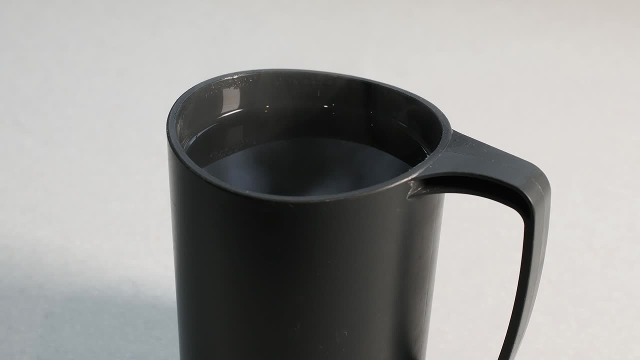 Primo piano di acqua fumante in una tazza di plastica blu su un tavolo.