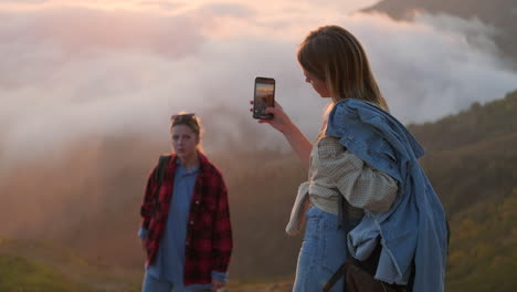 two friends taking a picture of a sunset over the mountains