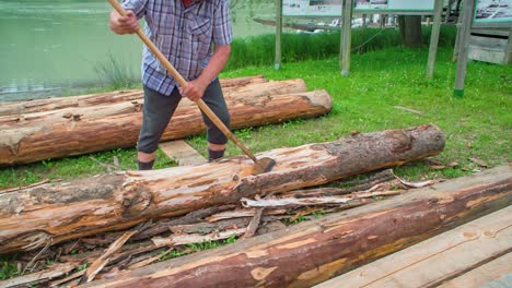 Slow motion shot of a traditional raftman wood chiselling beside Drava River in Slovenia