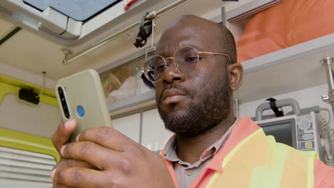 close up of american medical assistant texting and using his smartphone 1