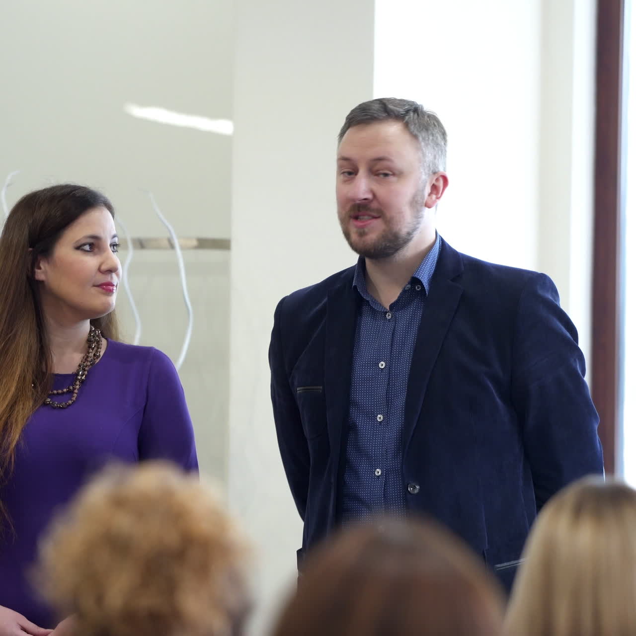 Businessman in suit conducting speech at public seminar. Man and woman talking to the audience during the conference. Business seminar.