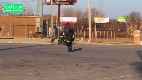 a rider performs stunts on a motorcycle in a parking lot