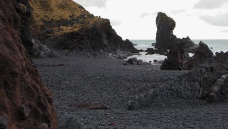 walking over the black rock beach of iceland by the waves - wide rolling