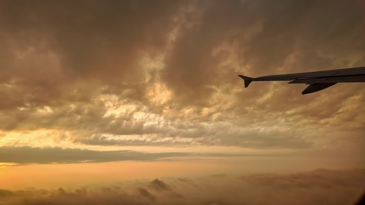 View from airplane window. Dawn flight with scattered clouds obscuring the sun