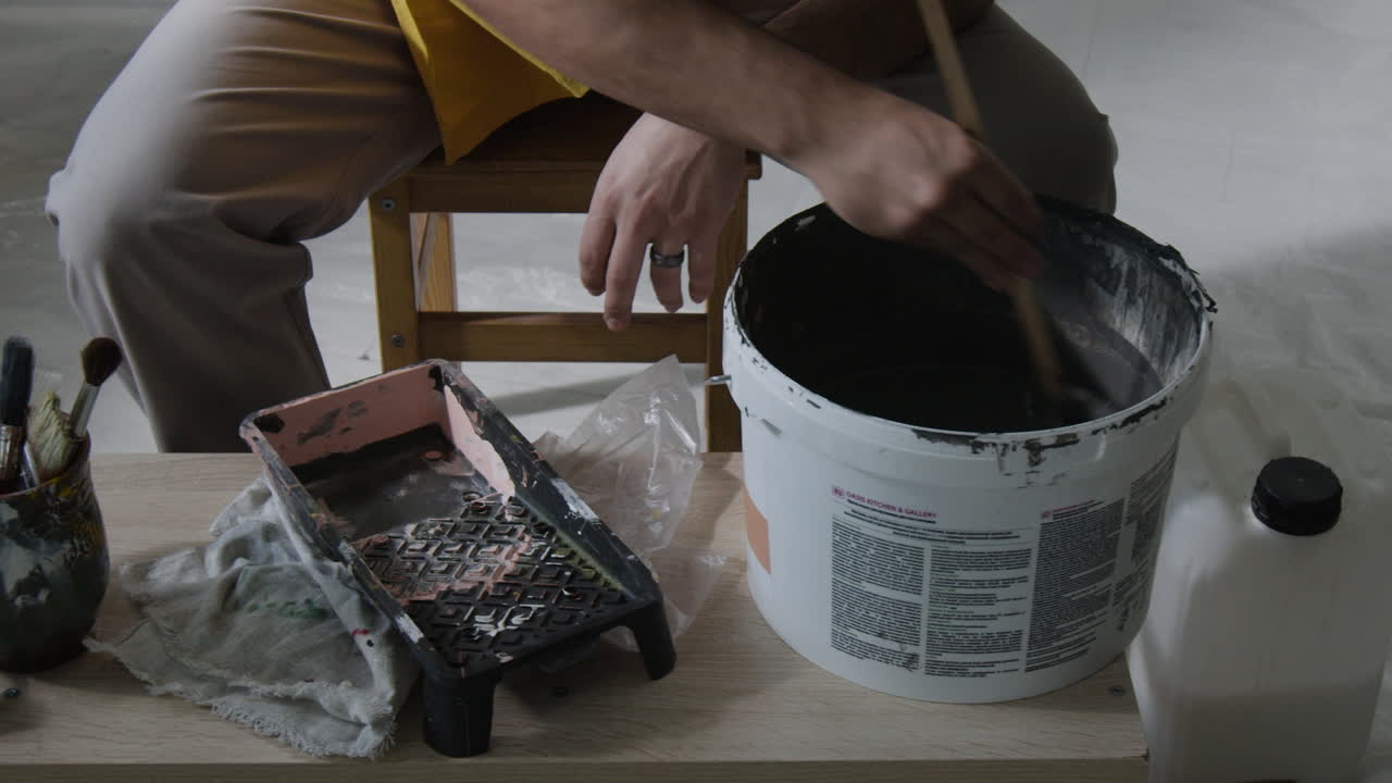 Person Stirring Paint in Bucket
