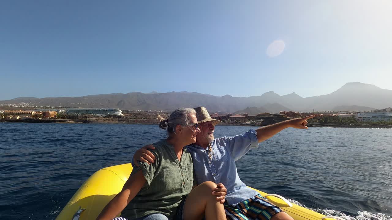 pareja de chicos maduros o ancianos disfrutando y divirtiéndose juntos en el medio del mar o el océano con un pequeño barco o bote - mujer jubilada tomando una selfie con su viejo conduciendo el barco