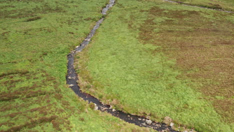 Toma-Aérea-Siguiendo-Un-Arroyo-En-El-Parque-Nacional-De-Las-Montañas-De-Wicklow-En-Irlanda