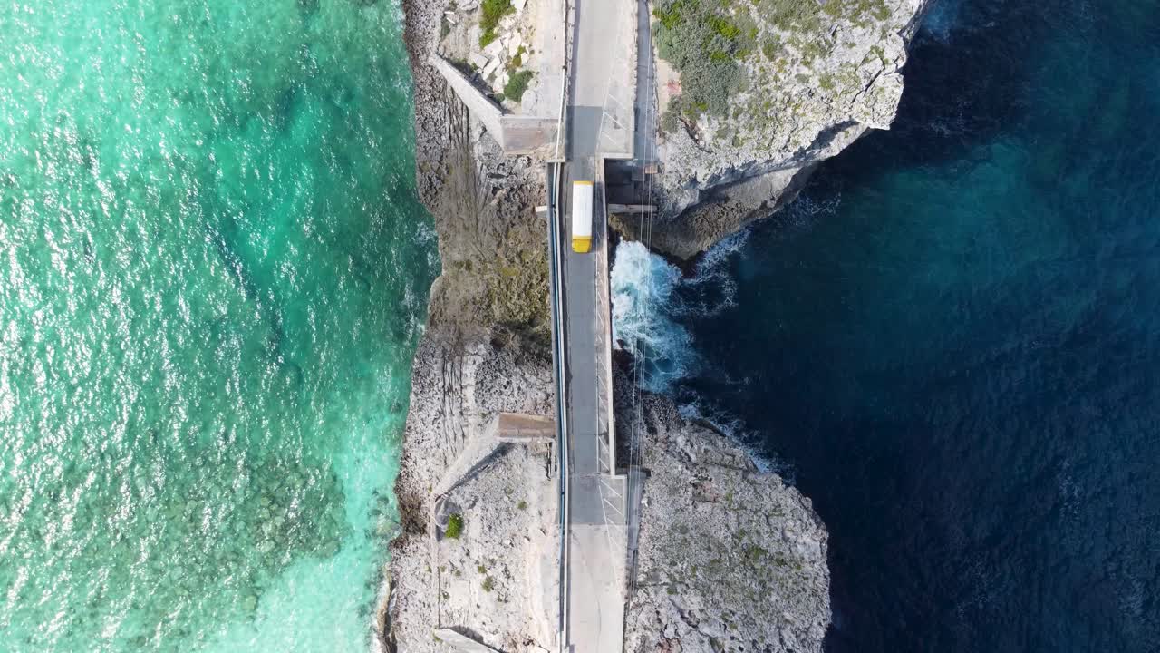Cinematic aerial view still top down drone shot of a bus crossing glass window bridge on the island of eleuthera in the bahamas - separating the atlantic ocean from the caribbean sea