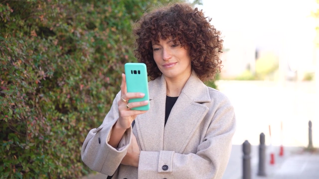 Una donna elegante con bellissimi capelli ricci, in abbigliamento casual, si gode una passeggiata all'aperto.