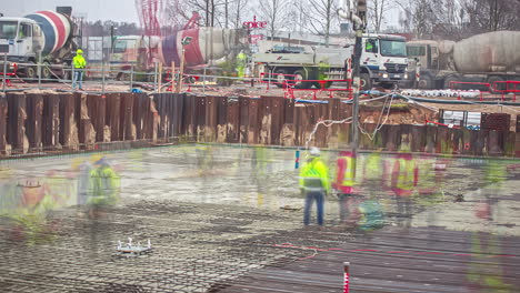 view of a busy building construction site in timelapse during autumn. workers working at a construction site in riga, latvia (2018)with many concrete mixer trucks lined up delievering cement