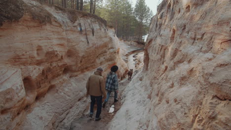 man and woman walking with dog in canyon