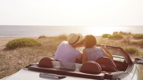 couple kissing in convertible car at beach sunset