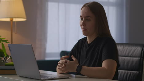 young-woman-is-conducting-webinar-by-laptop-from-her-home-communication-with-audience-by-webcam-looking-on-screen-and-gesticulating-online-lecture-of-specialist